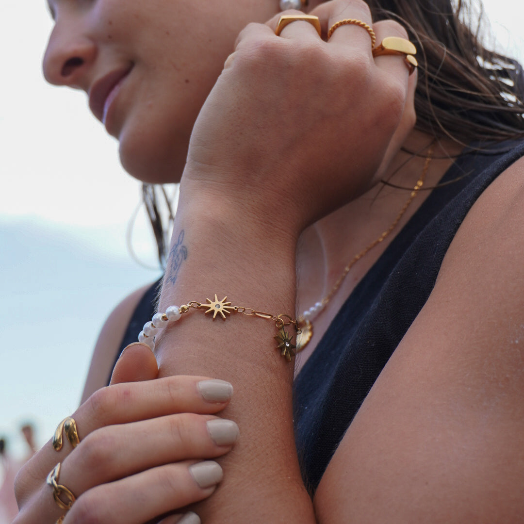 Woman wearing multiple pieces of jewelry including earrings, rings, and a bracelet.