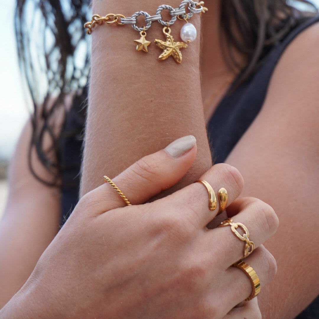 Close-up of a person's wrist and hand wearing gold jewelry with charms.
