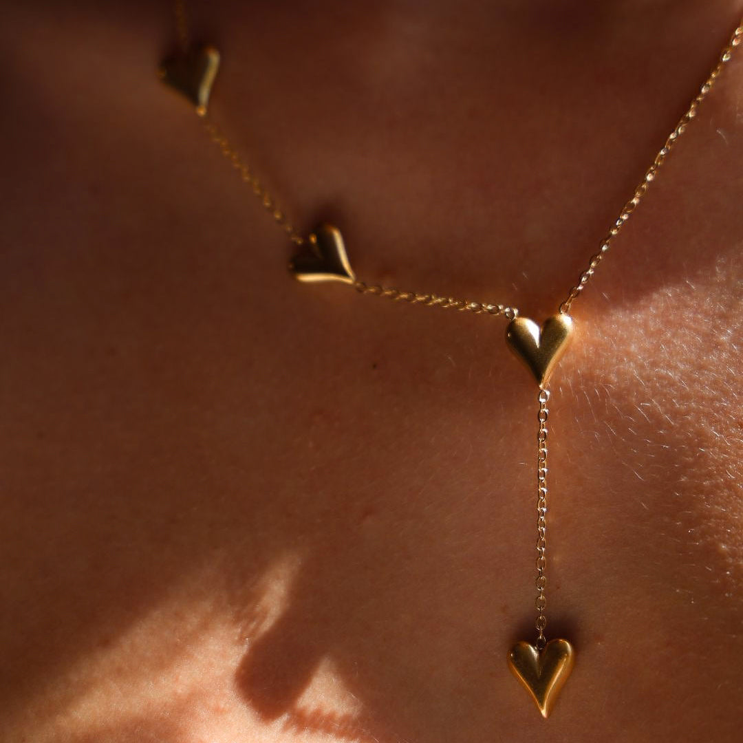 Gold necklace with heart pendants on a person's neck