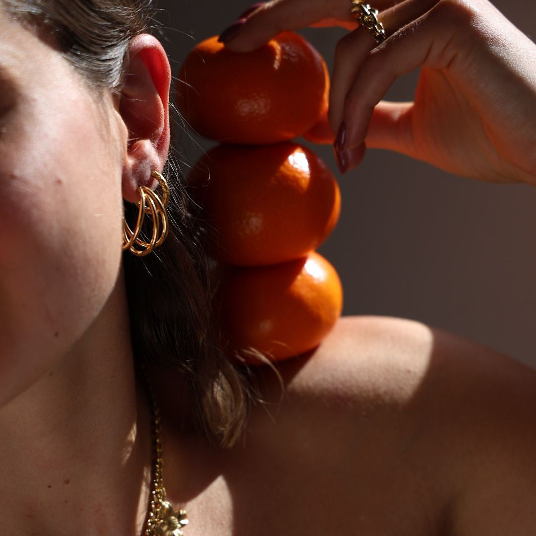 Woman wearing gold earrings and necklace with a blurred background
