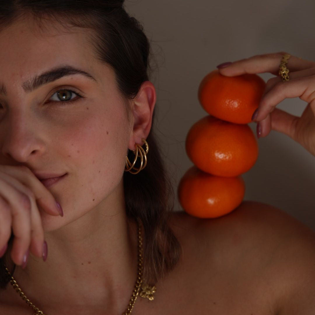Woman holding three tomatoes with a neutral background