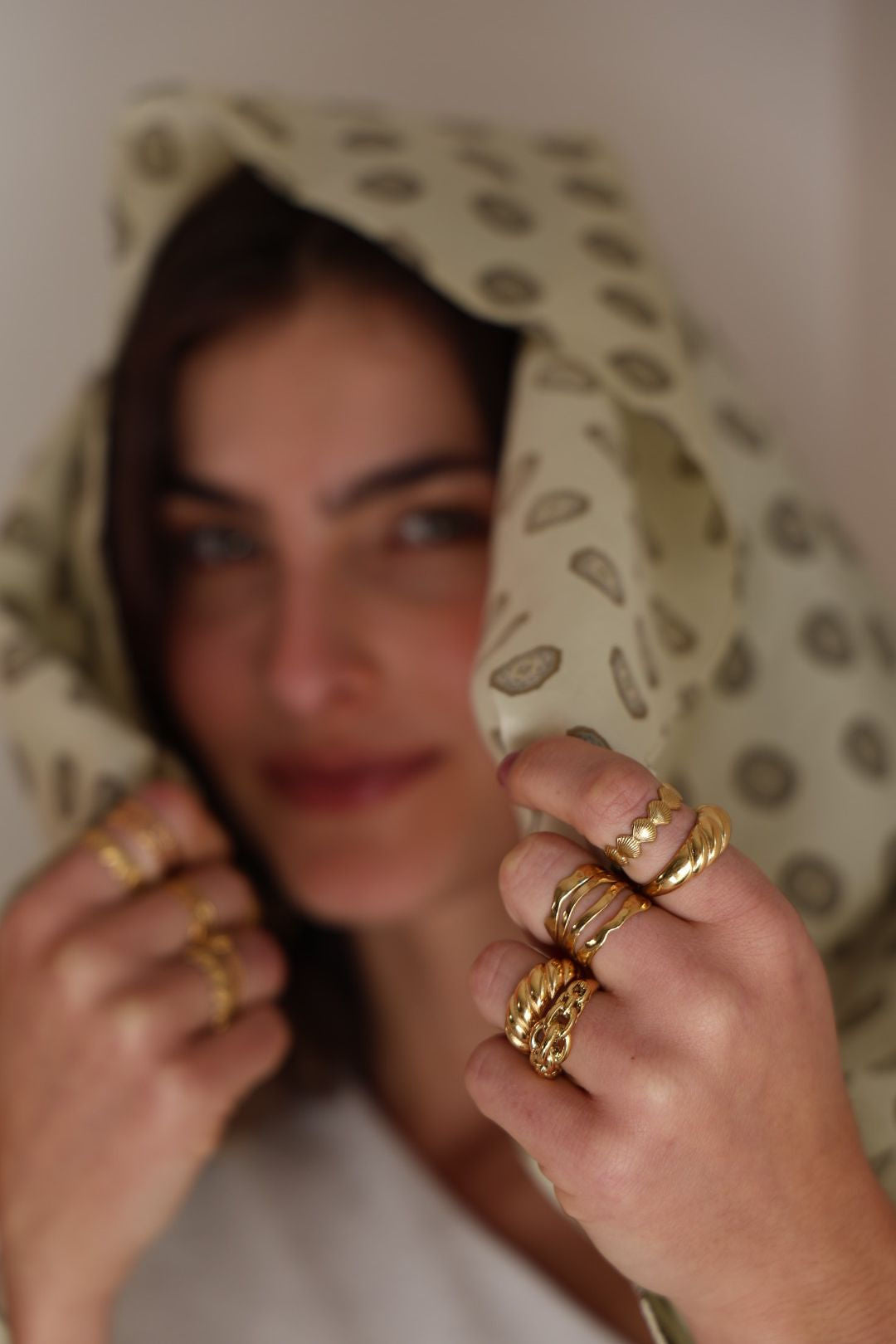 Woman wearing gold rings with a patterned headscarf