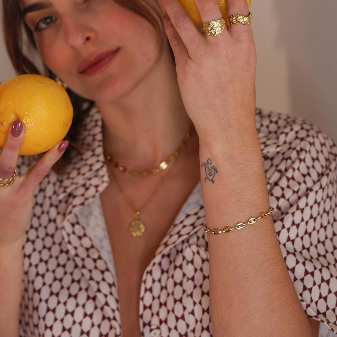 Woman holding two lemons in front of her face with a neutral background