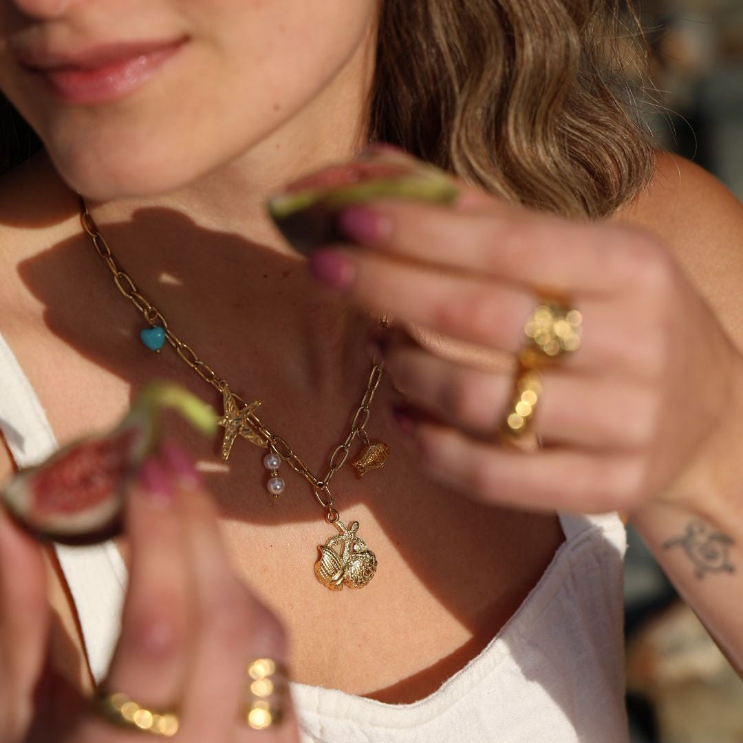 Woman holding a slice of fig with a necklace and rings in focus
