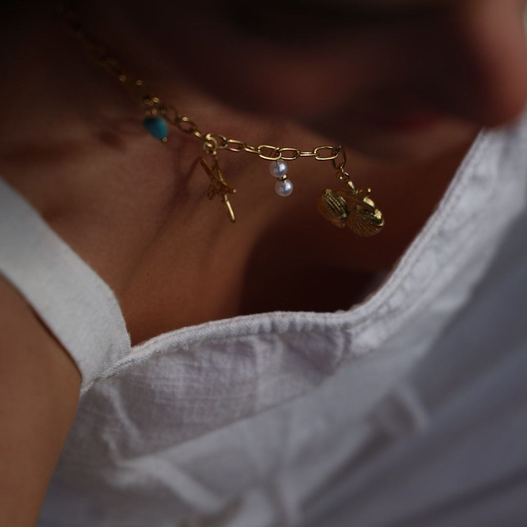 Close-up of a person wearing a gold necklace with charms.