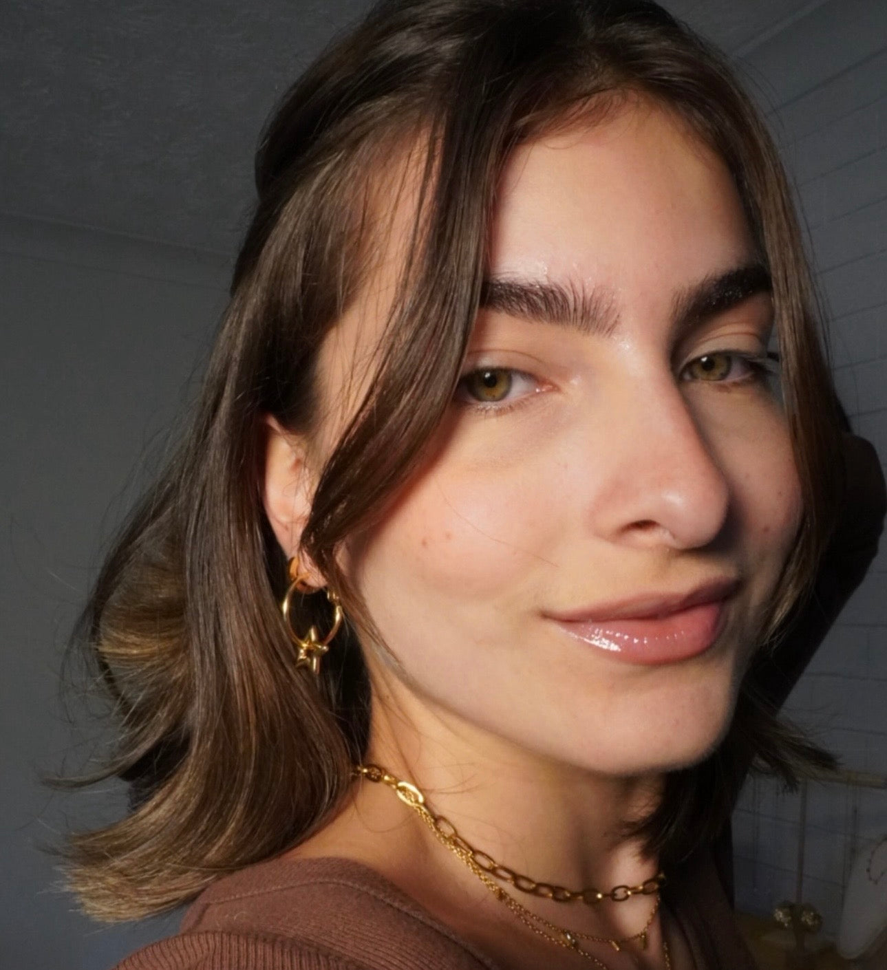 Gold star hoop earrings worn on ear, lightweight everyday waterproof jewelry