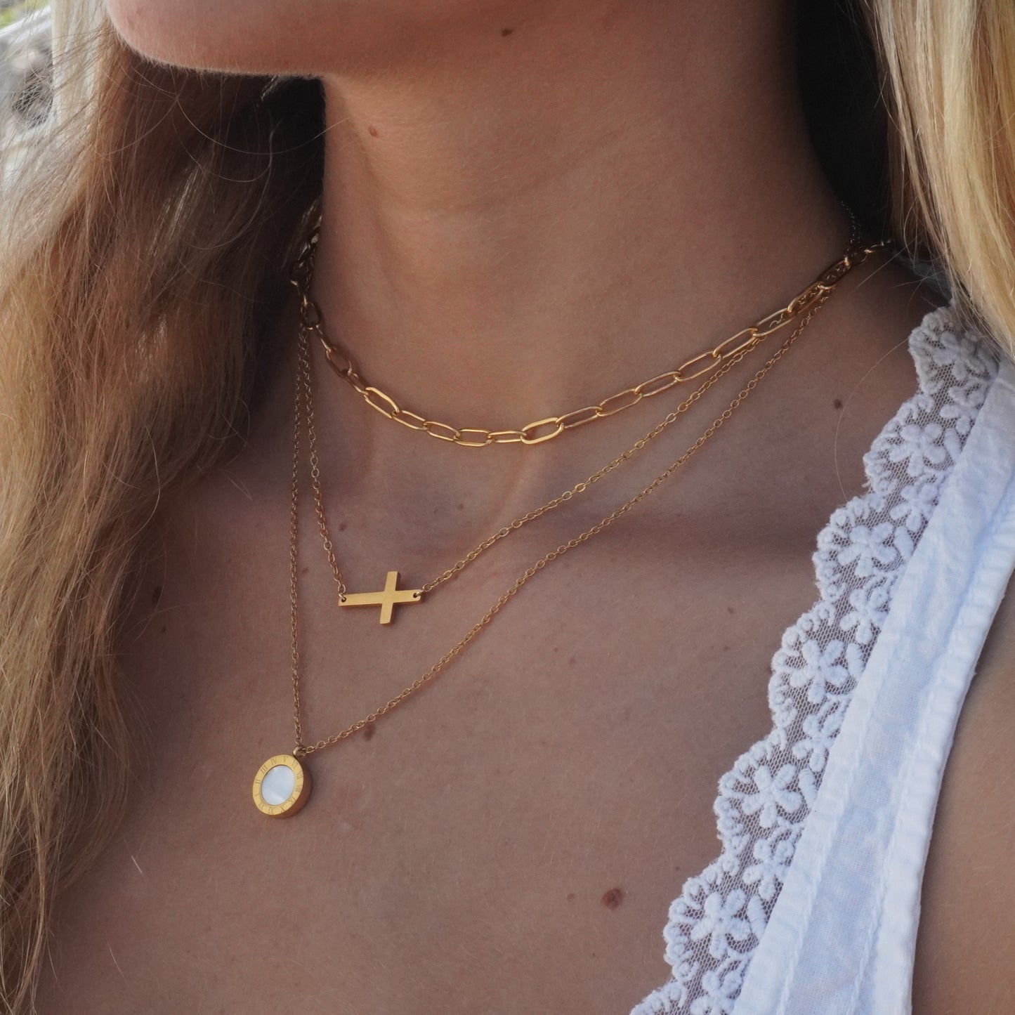 Close-up of a person wearing gold necklaces with a scenic background