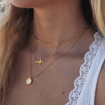 Close-up of a person wearing gold necklaces with a scenic background