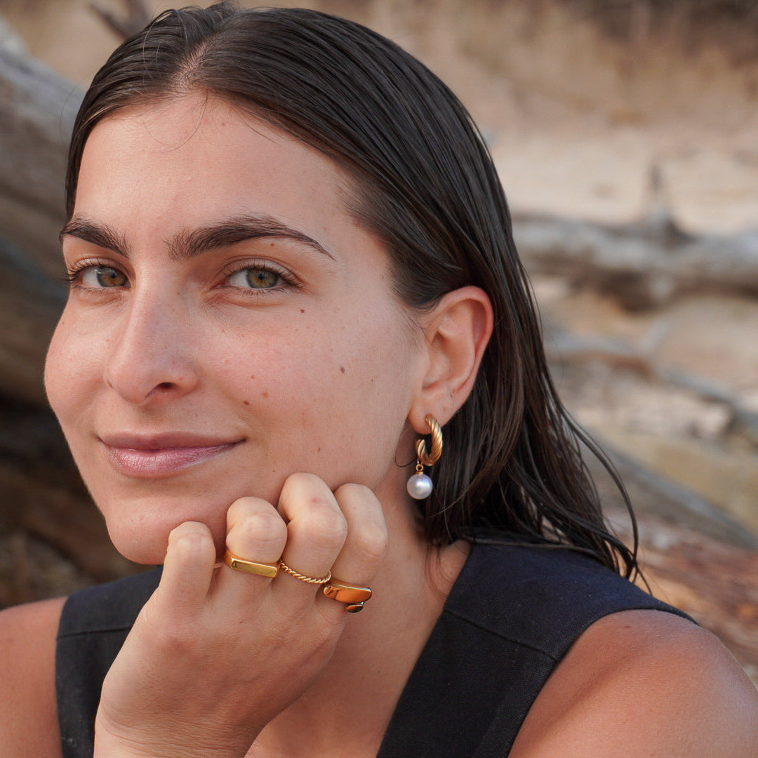Woman with earrings and a ring, standing outdoors with natural background