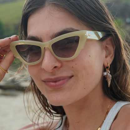 Woman wearing light-colored sunglasses with a blurred natural background