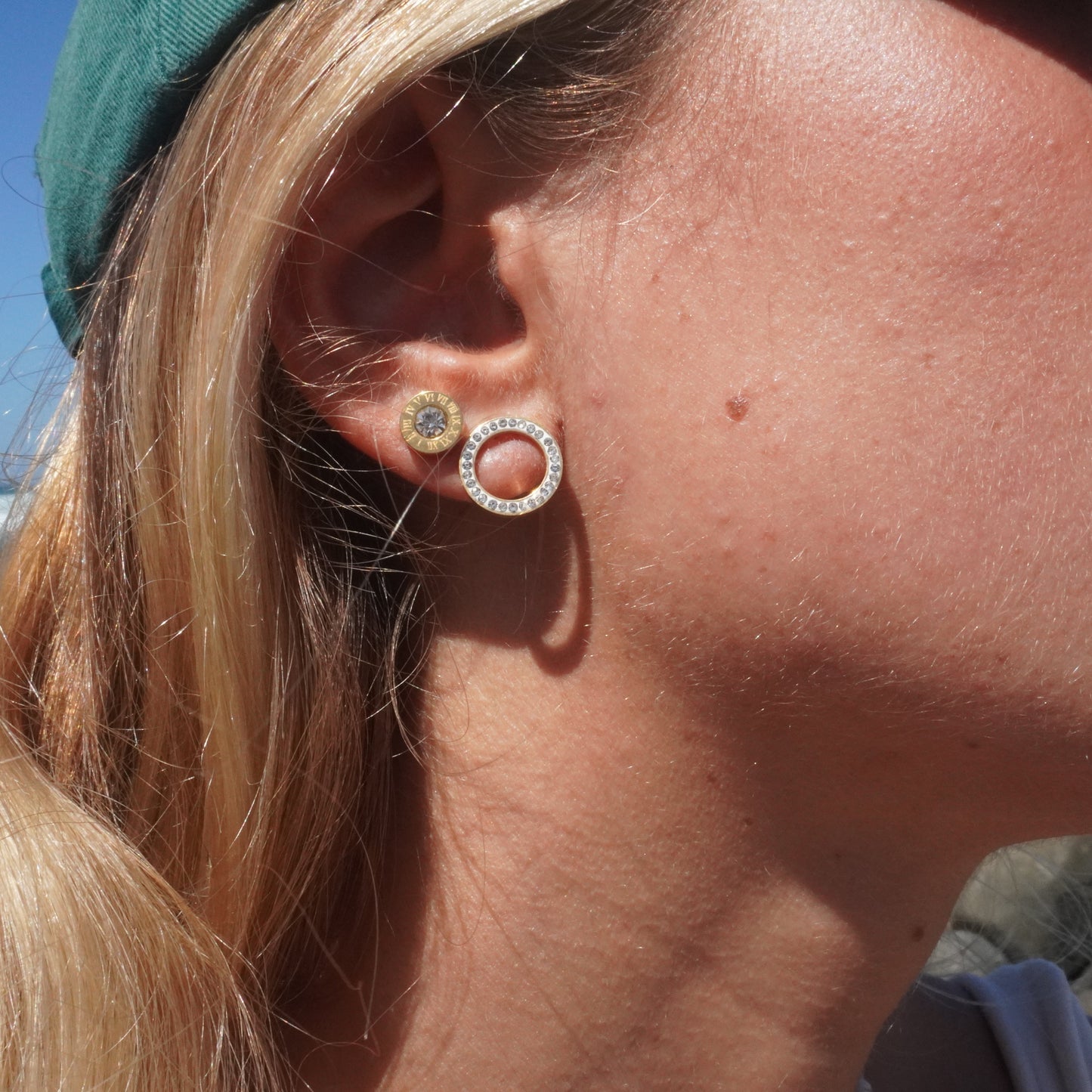 Close-up of a person wearing earrings with a beach in the background