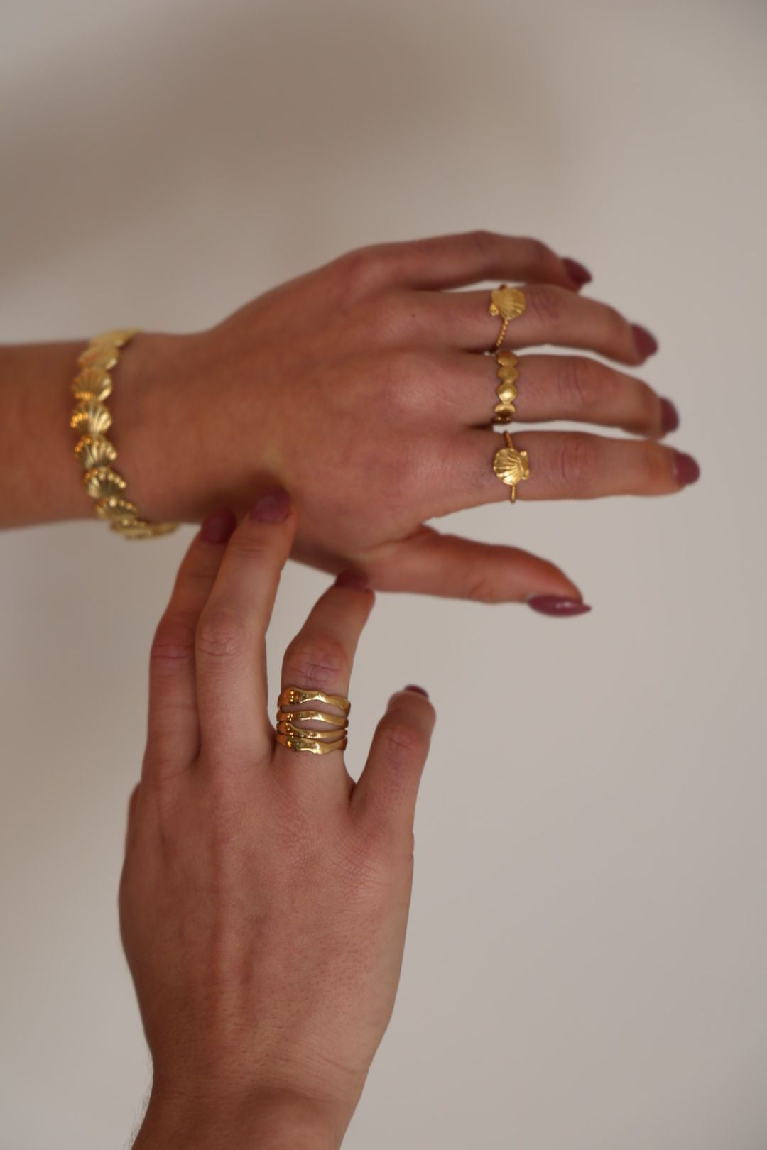 Close-up of a hand wearing gold jewelry on a plain background