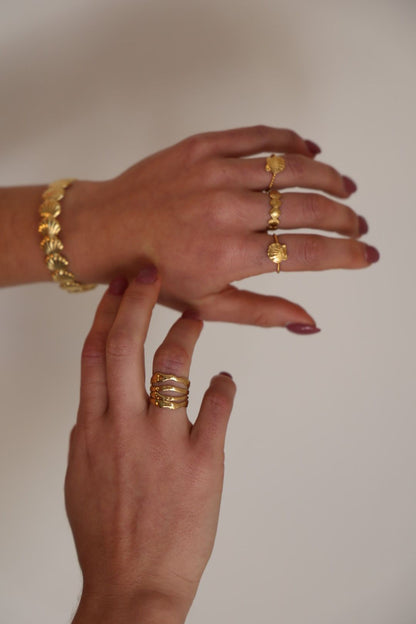 Close-up of a hand wearing gold jewelry on a plain background