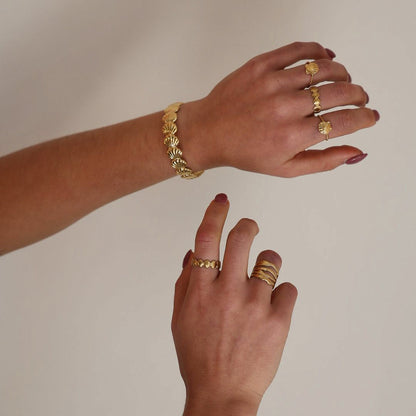 Close-up of hands wearing gold jewelry on a plain background