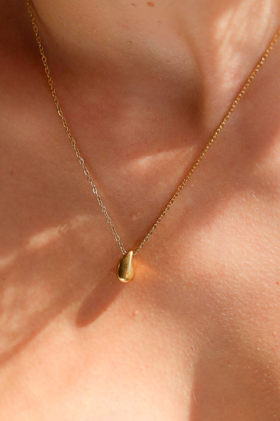 Gold necklace with a small pendant on a person's neck