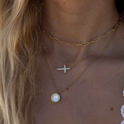 Close-up of a person wearing multiple gold necklaces with a blurred background