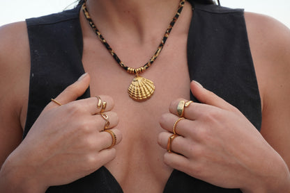 Model wearing the La Isla Necklace with gold shell pendant and stacked gold rings — waterproof 18K gold plated necklace from BR Jewelry.