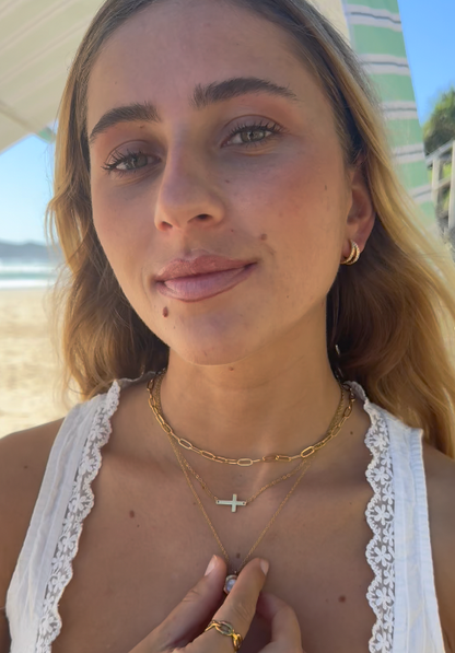 Woman with gold necklaces and earrings on a beach